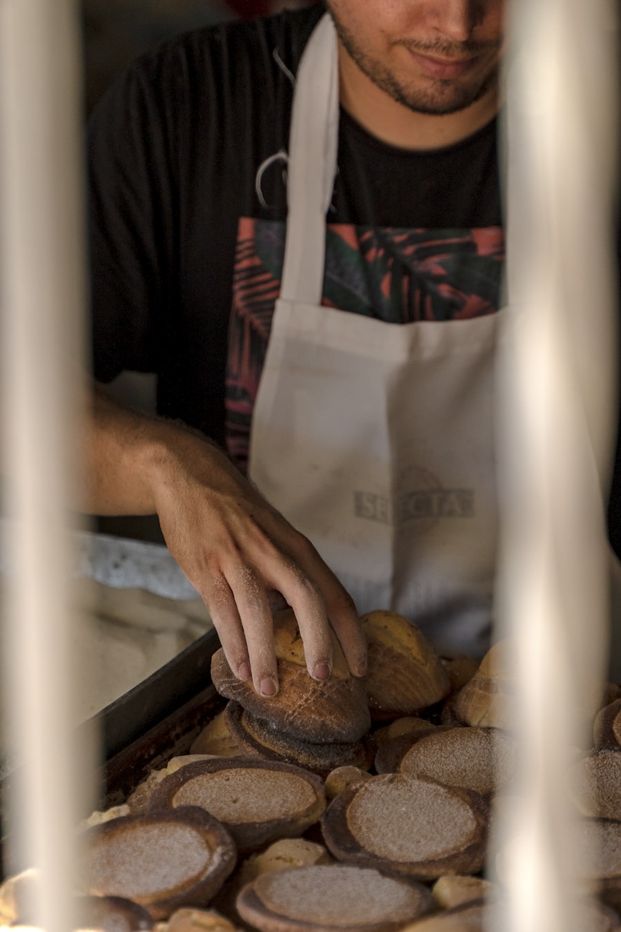 A baker in an apron placing fresh bread on a tray, working in a small kitchen. Stand-in image — replace with the real team portrait before launch.