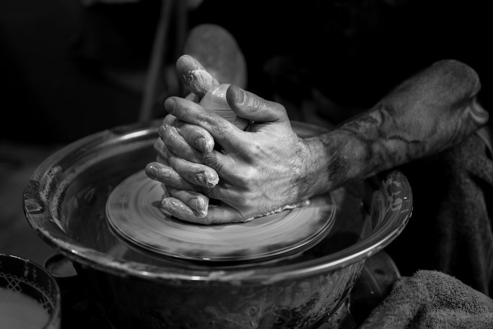 A potter hands shaping wet clay on a wheel, stoneware in progress