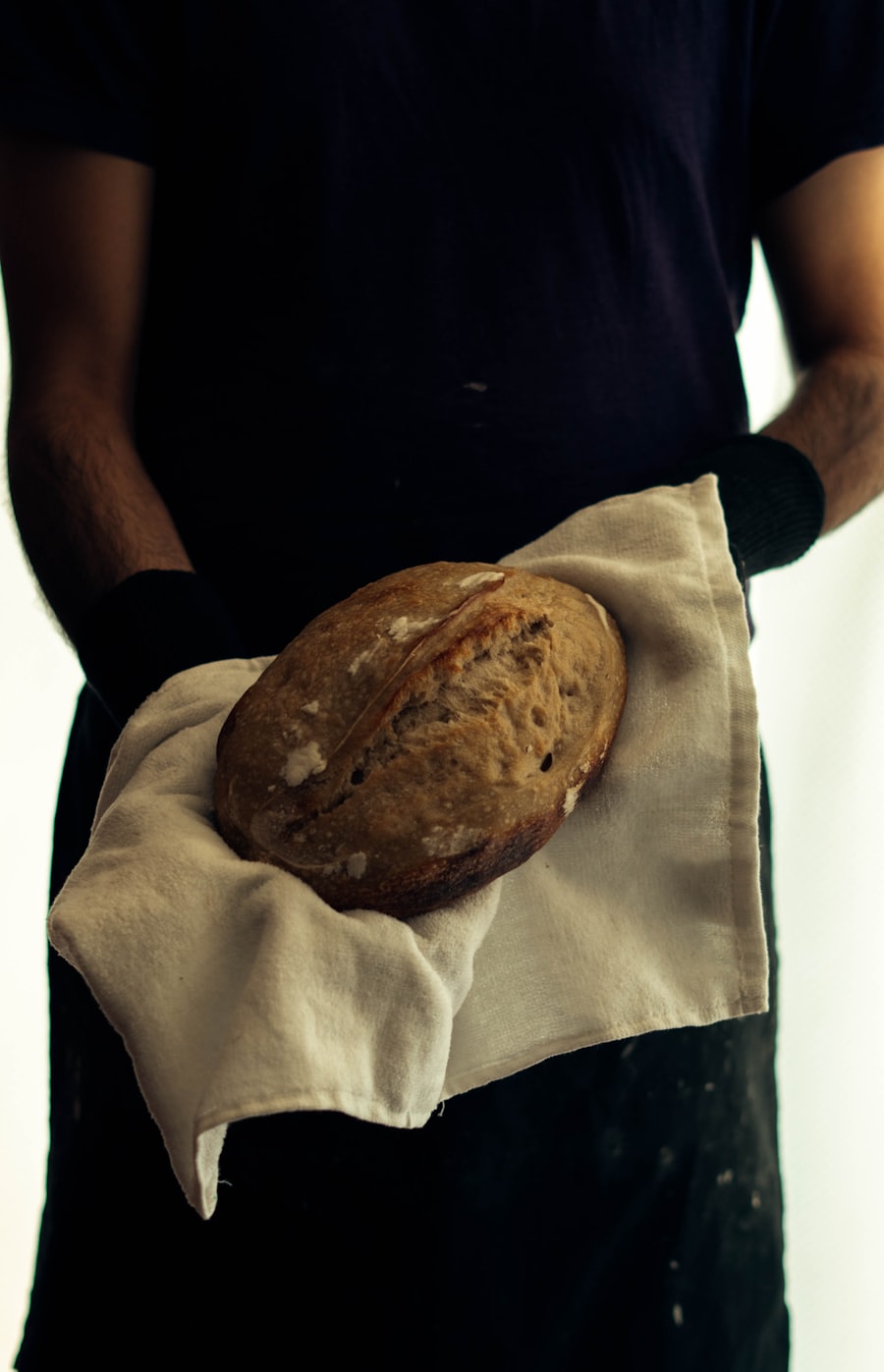 A baker holding a finished loaf of bread, candid, with a quiet smile. Stand-in image — replace with the real team portrait before launch.